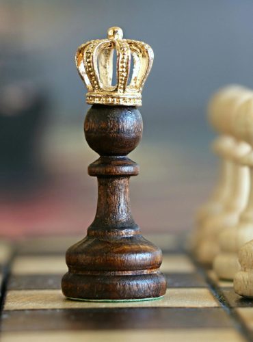 A brown pawn with a crown stands prominently on a chessboard, symbolizing strategic play.