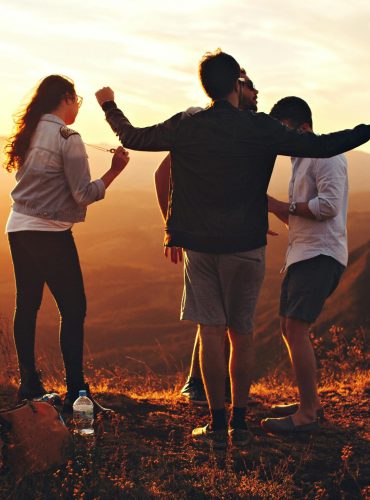 Joyful group of young adults enjoying a sunset view in a mountainous landscape in Brazil.